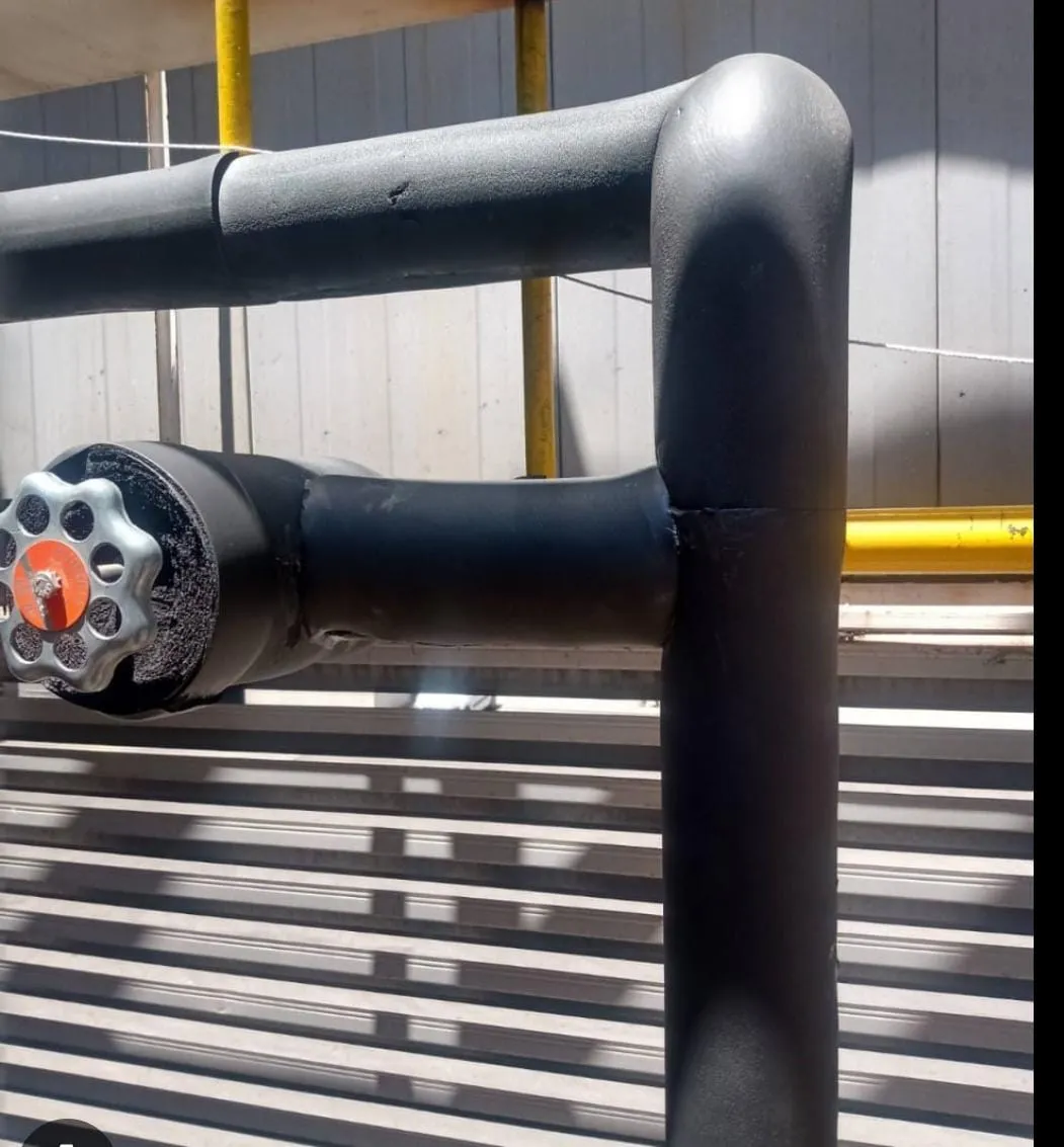 Aislamiento elastomérico negro en cañerías industriales con codo y válvula – Aislaciones DM
